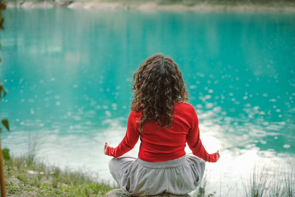 Woman practicing yoga outdoors by a serene lake